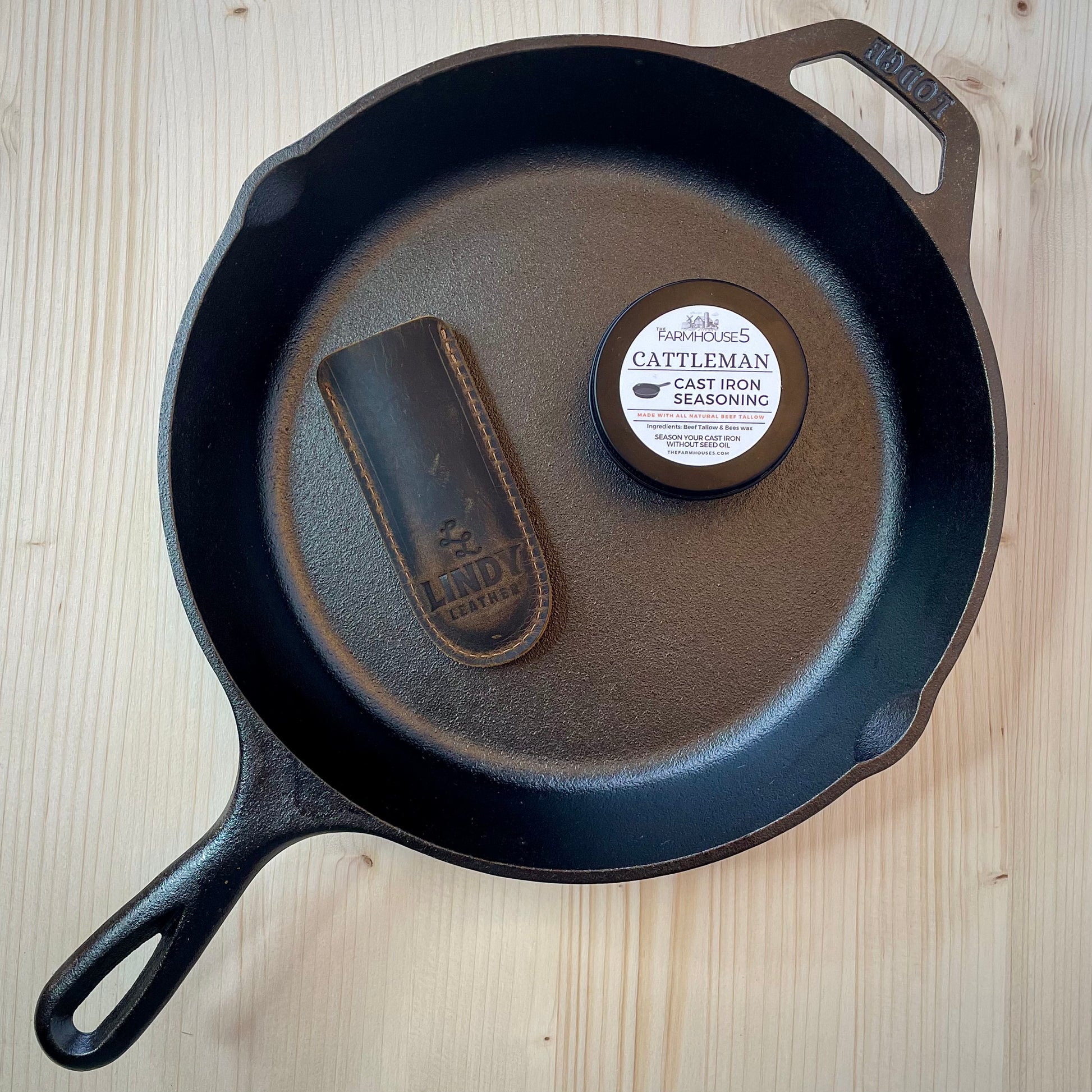 Pre-seasoned Lodge cast iron skillet with Cattleman seasoning tin and Lindy leather handle cover